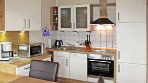 A compact kitchen with a microwave, coffee maker, sink, and oven. - Kleine Möwe by Interhome (Timmel)