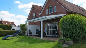 A two-story house with a covered patio, a lawn, and a hedge. - Kleine Möwe by Interhome (Timmel)