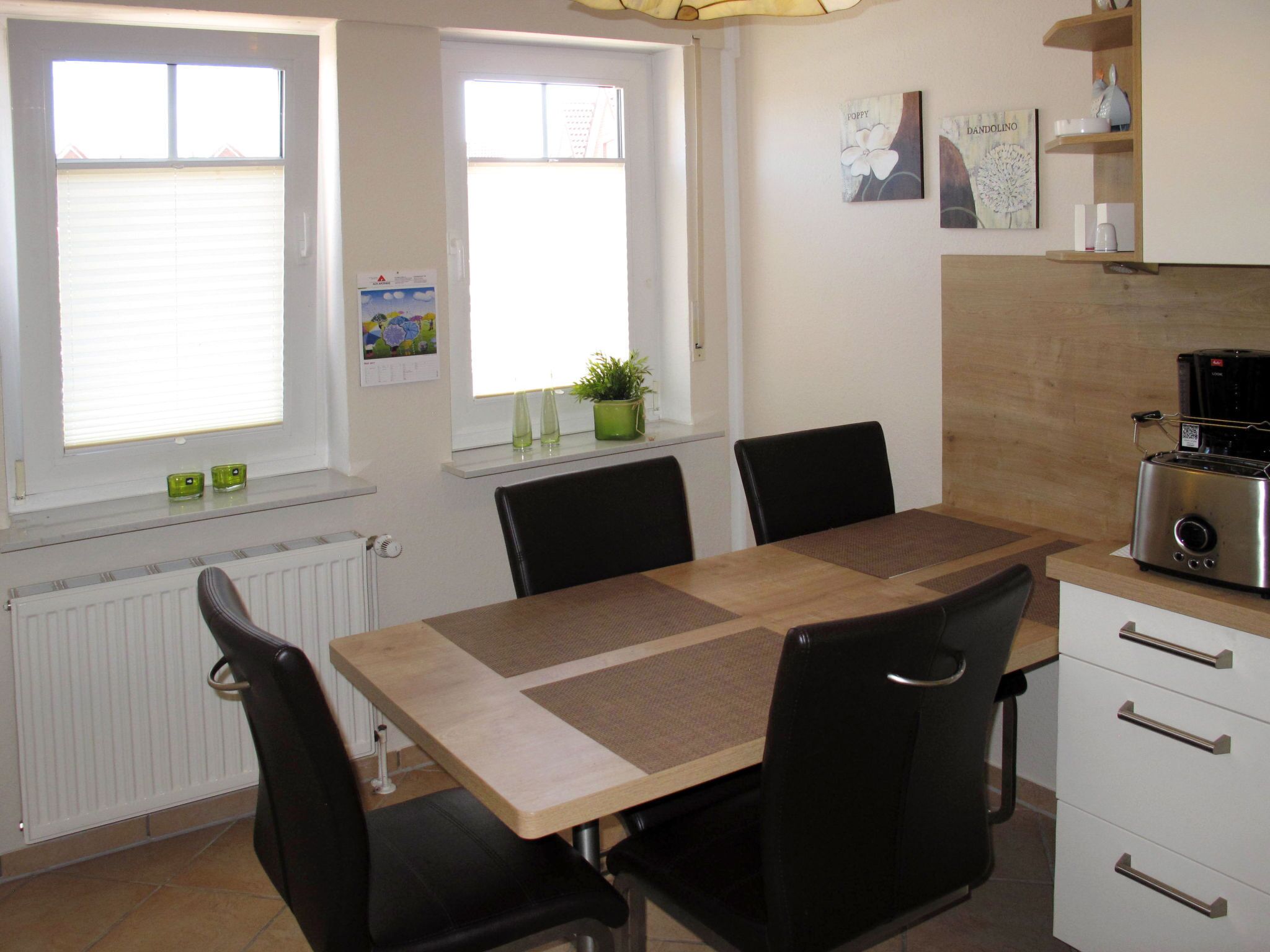 A kitchen with a wooden table, black chairs, a toaster, and a radiator.