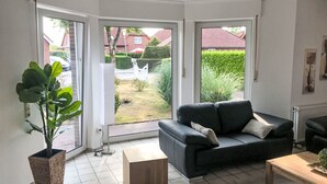 Een woonkamer met een zwarte bank, een houten salontafel en een potplant.