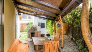 An outdoor patio with a wooden table and chairs, a stone fireplace, and a wooden fence. - Vacation home Jiri by Interhome (Dehtáře)