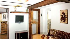 A cozy living area with a wooden ceiling, a television mounted on the wall, a sofa, and a small round table with cups. - Vacation home Jiri by Interhome (Dehtáře)