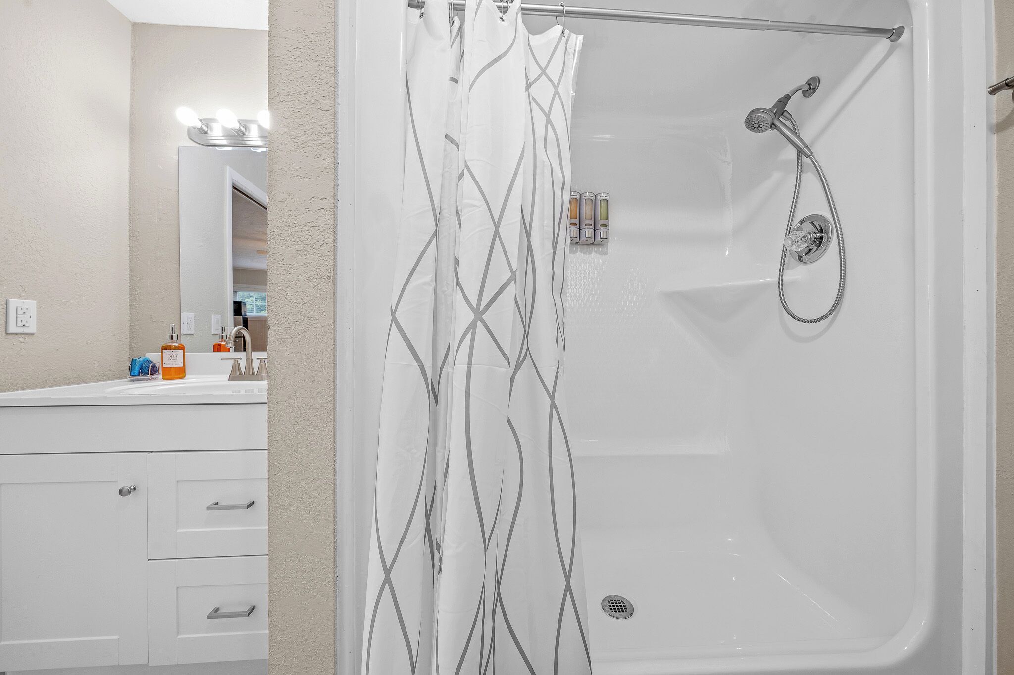 A modern bathroom with a shower, a vanity with a mirror, and toiletries.