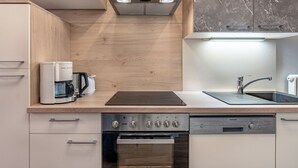 A modern kitchen with a built-in oven, dishwasher, and a coffee maker on the countertop. - Ferienglück by Interhome (Arriach)