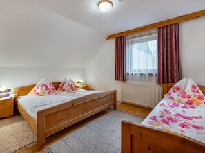 A bedroom with two wooden beds, a window with curtains, a nightstand with a lamp, and a radiator. - Herzele by Interhome (Arriach)