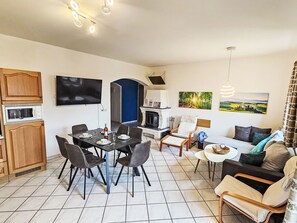 A modern living room with a dining area, a fireplace, and a TV.