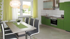 A modern kitchen with green cabinets, a stainless steel oven, and a dining area with a table and chairs.