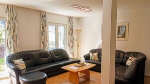 Ein Wohnzimmer mit zwei schwarzen Ledersofas, einem Holztisch und einer Stehlampe.