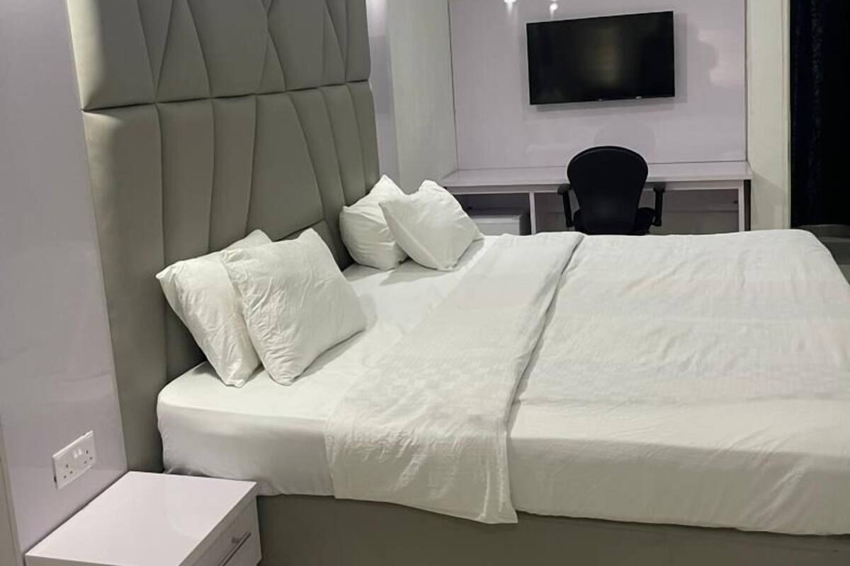A modern bedroom with a large bed, a desk, and a TV.