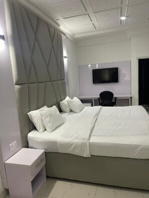 Een moderne slaapkamer met een groot bed, een bureau en een televisie.