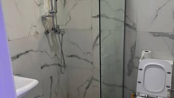 Un bagno con doccia vetro-ceramica, un water e un lavandino.
