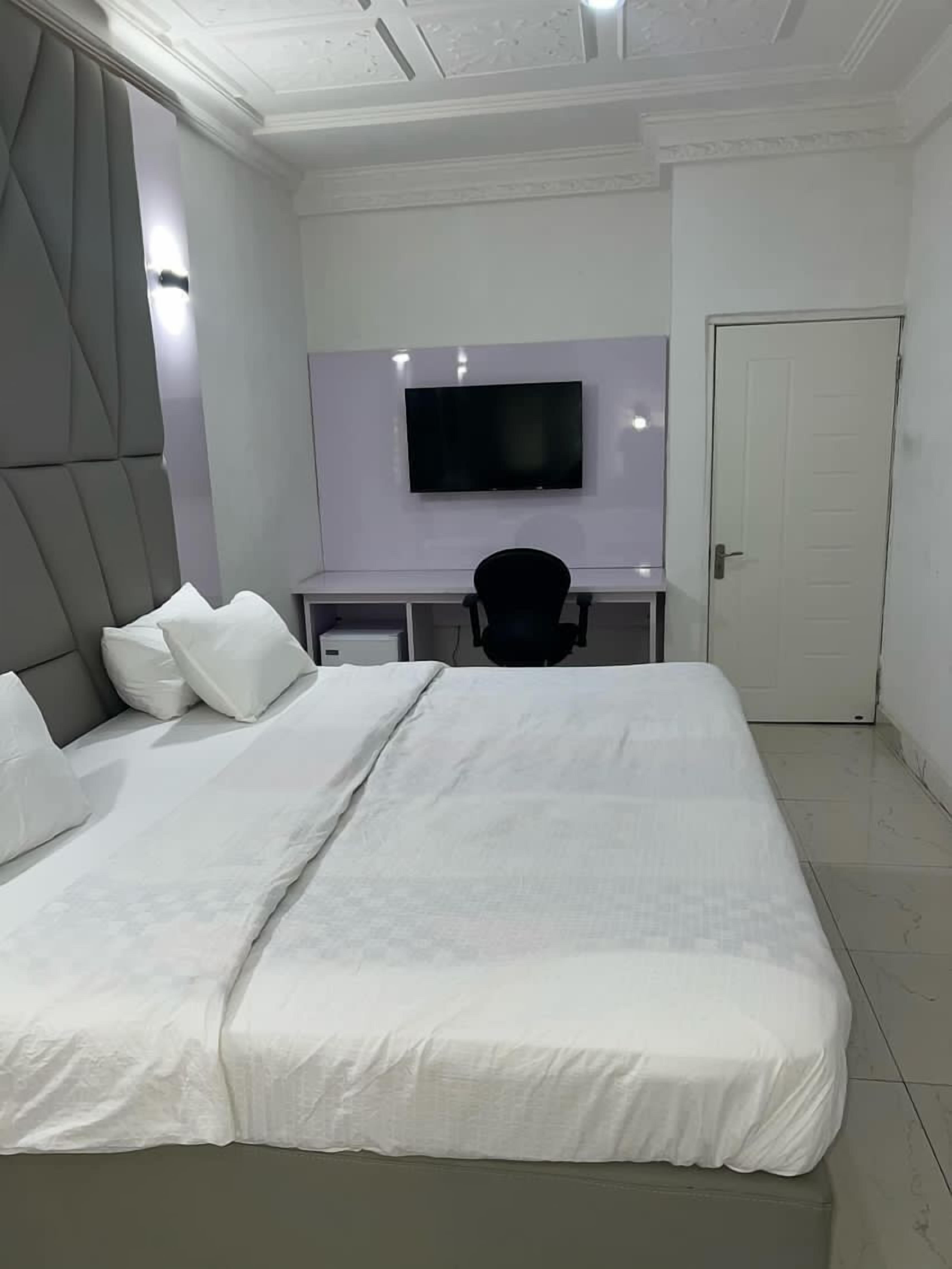 Ein modernes Schlafzimmer mit einem großen Bett, einem Schreibtisch und einem Fernseher.