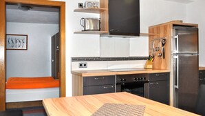 A compact kitchen with a wooden countertop, a built-in oven, a refrigerator, and a microwave.