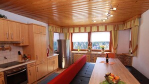 Une cuisine dotée de meubles en bois, d’un réfrigérateur, d’une cuisinière et d’un coin repas avec un banc et une table.