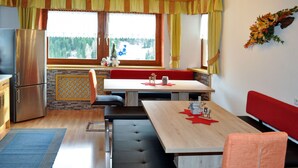 Une cuisine chaleureuse avec un coin repas, comprenant une table en bois, des bancs et un réfrigérateur.
