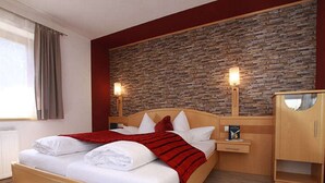 Une chambre d’hôtel avec un lit en bois, un mur en pierre et une table de chevet avec une lampe.