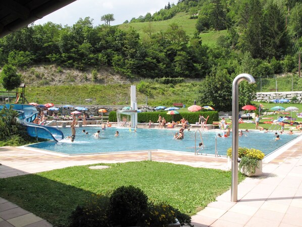 Relax by the pool surrounded by lush greenery and shaded by umbrellas.
