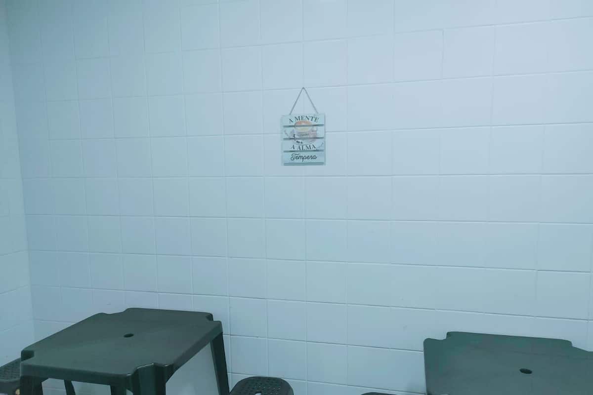A bathroom with white tiled walls, a hanging sign, and two green stools.
