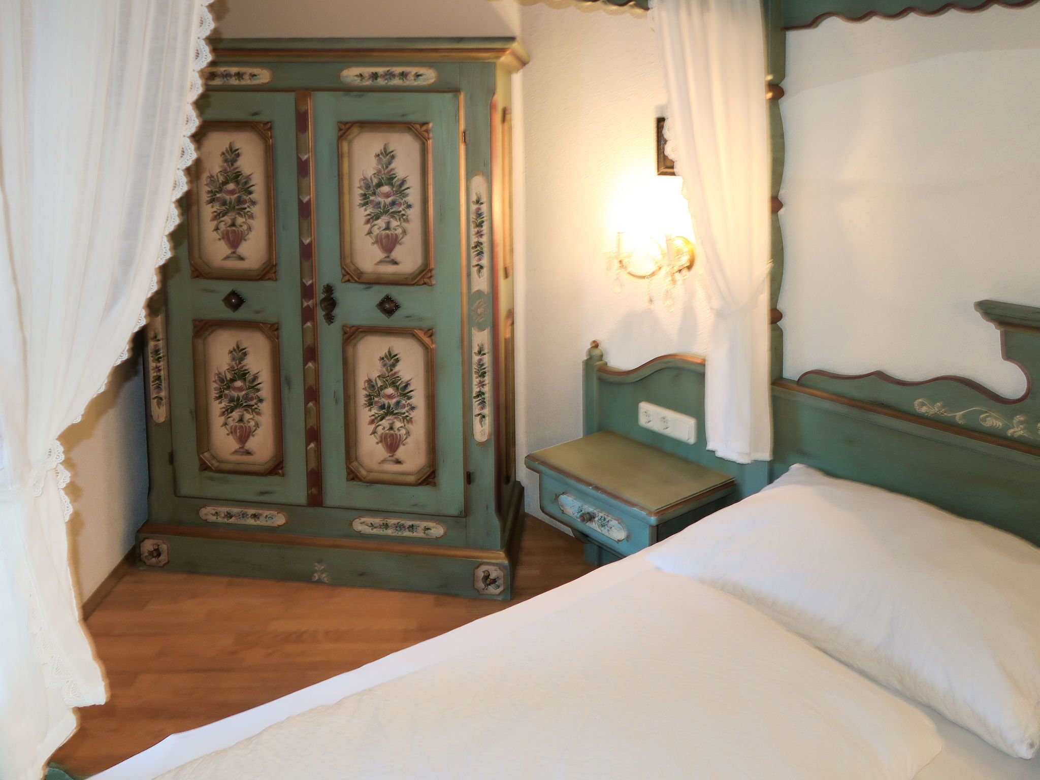 A bedroom with a bed, a nightstand, and a wardrobe.