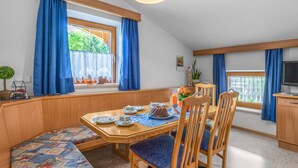A cozy dining area with a wooden table, blue curtains, and a bench. - Apartment Markus by Interhome (Zell am Ziller)