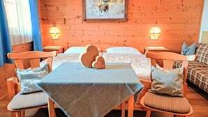 A cozy wooden room with a bed, two chairs, a table, and a couch.