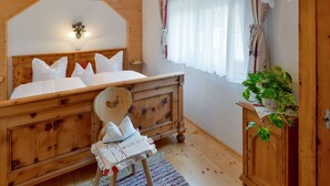 A wooden bedroom with a bed, a nightstand, a chair, and a wardrobe.