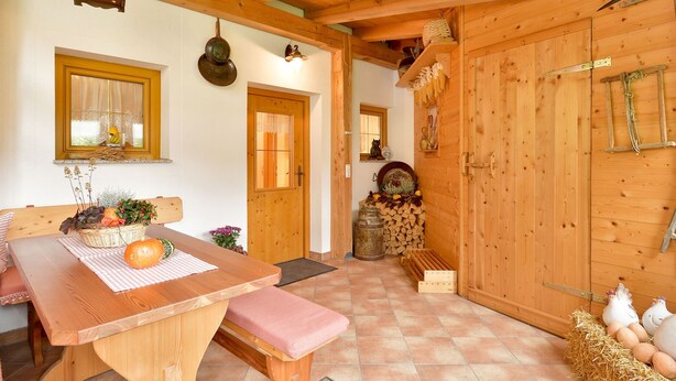 A wooden interior with a dining table, bench, and a rustic wooden door.