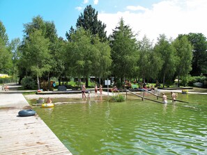 A public park with a wooden deck, a small pond, and people swimming and relaxing. - Waldfrieden by Interhome (Mondsee)
