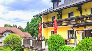 Ein gelbes Gebäude mit Balkon, roten Sonnenschirmen und einer Beschilderung mit der Nummer 39.