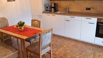 Eine moderne Küche mit weißen Schränken, einer Holz Arbeitsplatte und einer Kaffeemaschine.