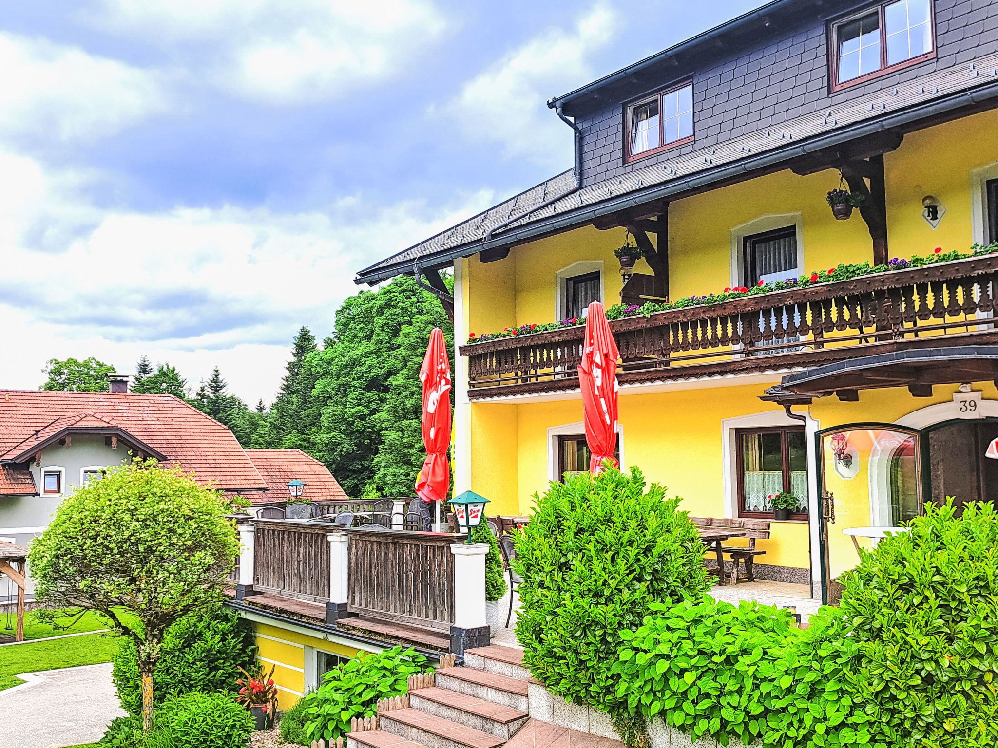 Ein gelbes Gebäude mit Balkon, roten Sonnenschirmen und einer Beschilderung mit der Nummer 39.