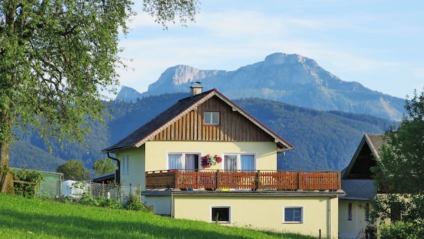 A two-story house with a wooden balcony, surrounded by lush green grass and mountains in the background. - Mayrhofer by Interhome (Mondsee)