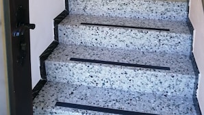 A staircase leading to a door with a 'WELCOME' sign, a bulletin board with notices, and a small plant decoration. - Mayrhofer by Interhome (Mondsee)