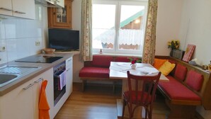 A compact kitchen with a dining area, wooden cabinets, a built-in oven, and a television. - Mayrhofer by Interhome (Mondsee)