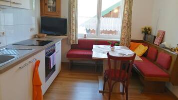 Een koelkast, een oven, een broodrooster, kookgerei, borden en bestek