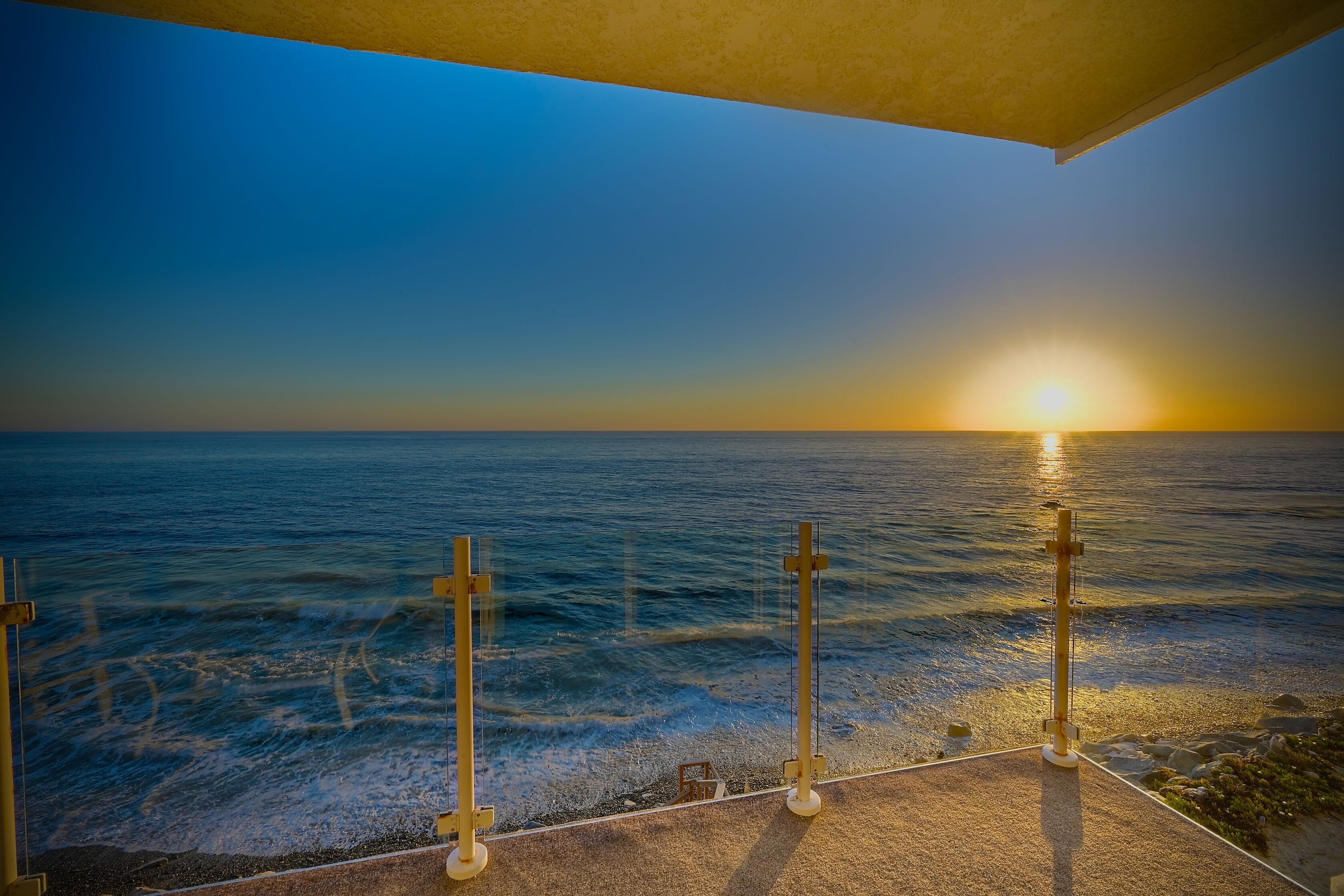 Une vue sur le coucher de soleil depuis un balcon donnant sur l’océan.