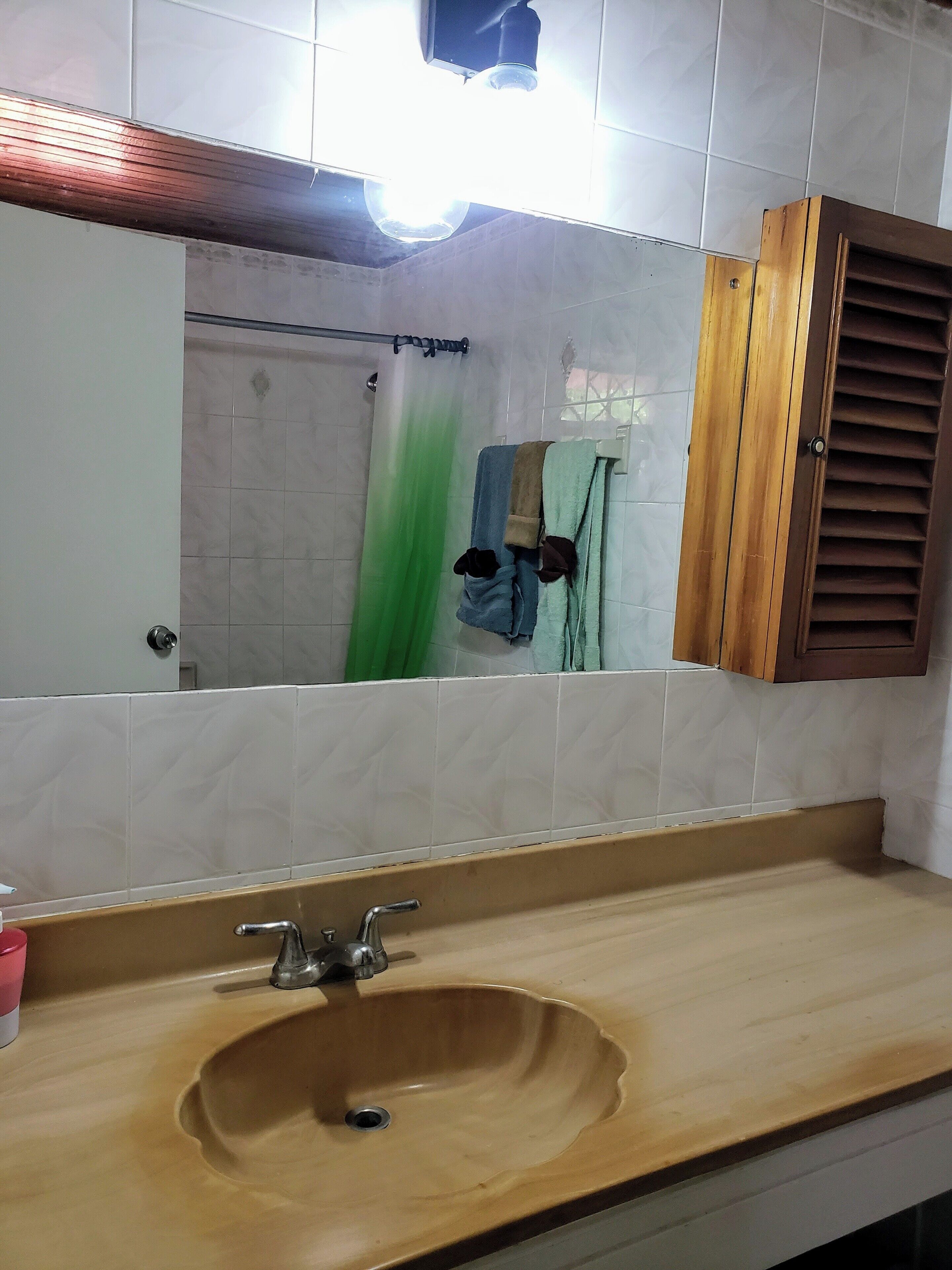 A bathroom with a wooden sink, a mirror, and a shower curtain.