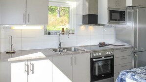 Una cocina moderna con electrodomésticos de acero inoxidable, un ventanal con vista a zonas verdes y una encimera con un hervidor.