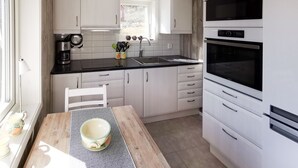 Een moderne keuken met witte kasten, een zwart aanrecht en roestvrijstalen apparatuur, waaronder een koffiezetapparaat en een oven.