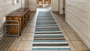 A hallway with wooden walls, a bench, a table, and a patterned rug. - Erikstorp 143 by Interhome (Olofström)