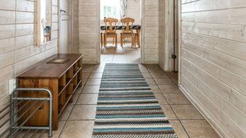 Un couloir aux murs en bois, avec un banc, une table et un tapis à motifs.