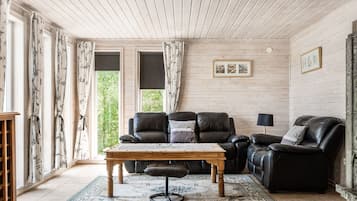 Un salon chaleureux avec un plafond en bois, un canapé en cuir, une table basse en bois et un tapis à motifs.