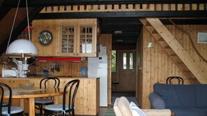 Un intérieur en bois comprenant un coin cuisine, une table à manger, des chaises et un canapé.