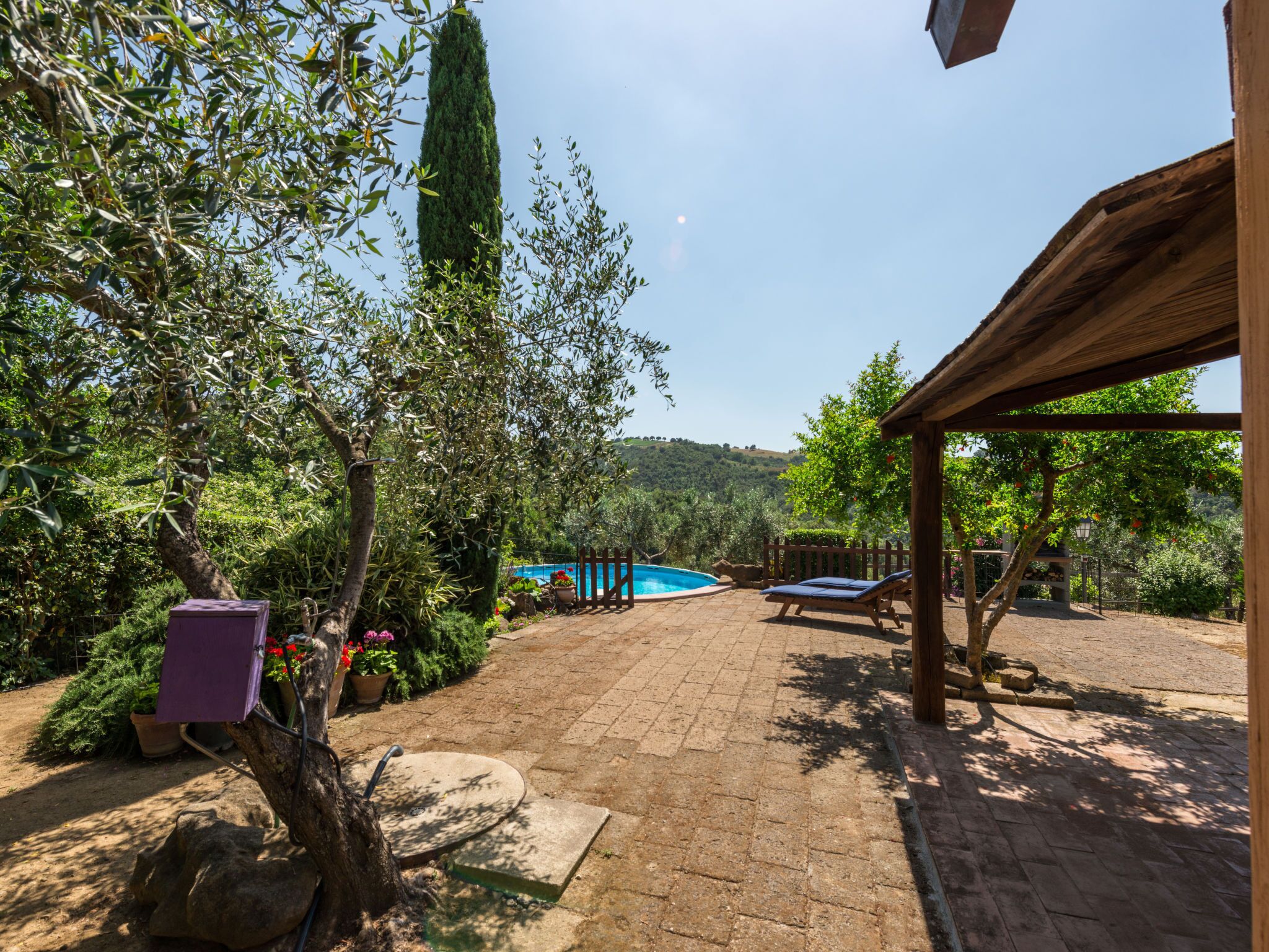 A patio area with a pool, outdoor seating, and a view of the surrounding landscape.