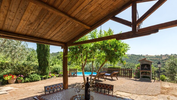 Un patio extérieur abrité, doté d’une table à motifs de mosaïque, de chaises longues et d’un barbecue.