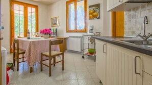 Une cuisine avec un coin repas, des meubles de rangement en bois, une fenêtre avec vue et un tableau au mur.
