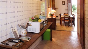 A kitchen with a wooden countertop, a microwave, and a dining area with a table and chairs. - Rondini by Interhome (San Polo in Chianti)