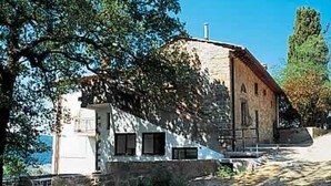 Ein rustikales Steinhaus mit geneigtem Dach, Schornstein und kleiner Veranda.