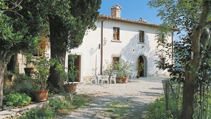 A white building with a tiled roof, a central archway, and potted plants in the foreground. - Vacation home Chiesa by Interhome (San Polo in Chianti)