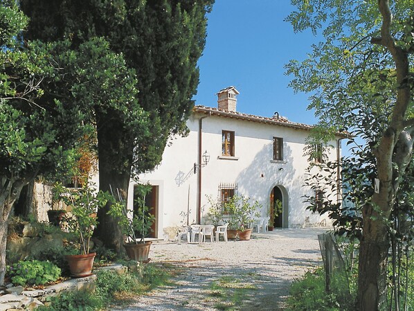 A white building with a tiled roof, a central archway, and potted plants in the foreground. - Vacation home Chiesa by Interhome (San Polo in Chianti)